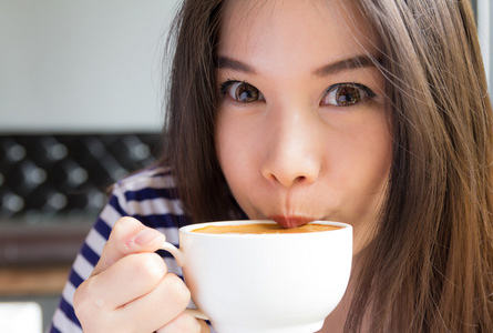 美丽的女人喝着卡布奇诺咖啡图片