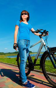 年轻的女人正站在她的自行车前面