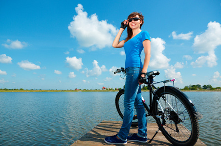 年轻的女人正站在她的自行车前面