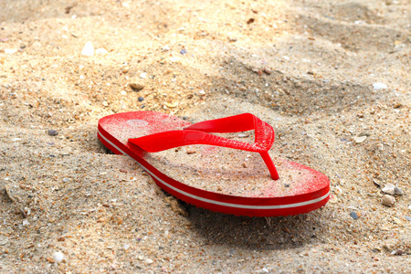 红色橡胶人字拖鞋在沙滩上
