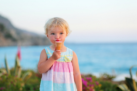 可爱的蹒跚学步的女孩享受暑假户外庆祝佳节吃冰激淋