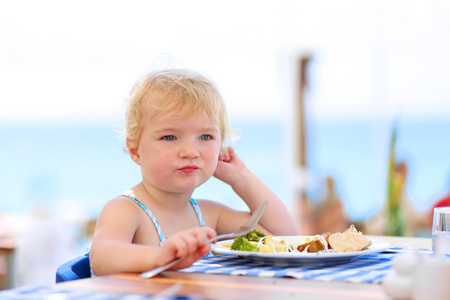 可爱的小女孩，在沙滩旁边的餐厅共进晚餐