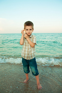 壳牌在傍晚的海滩上的小男孩