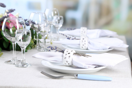 用薰衣草花在桌子上，在明亮的背景上餐桌设置。熏衣草婚礼概念
