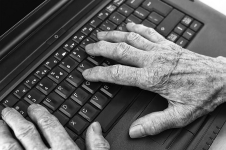 老人双手在键盘上的笔记本电脑