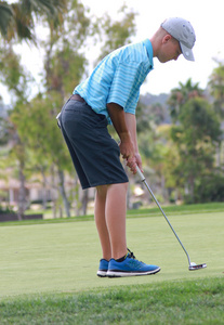 男性青少年高尔夫球手准备推杆