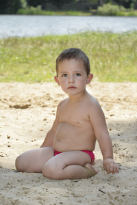 小女孩坐在海滩上的沙子湖附近