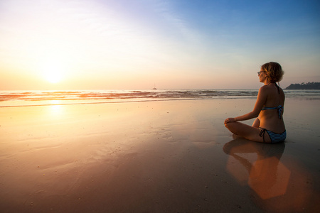 瑜伽女人坐在海岸上