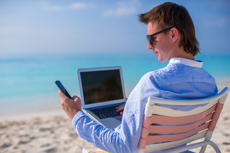 年轻的商人，在热带的海滩上使用便携式计算机