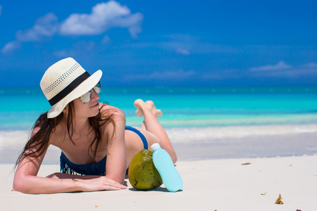 美丽的年轻女子抱着躺在热带海滩上防晒霜