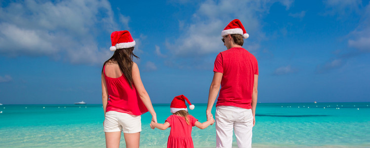 幸福的家庭，在白色沙滩上玩乐的圣诞帽