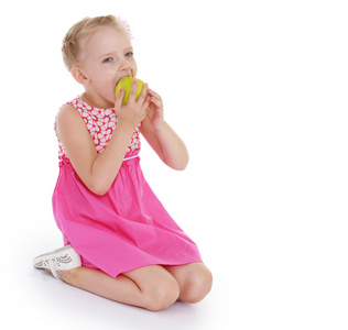 在粉红色的连衣裙吃苹果的女孩