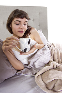 在早晨喝咖啡在床上的女人