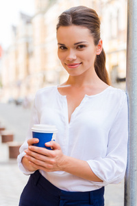 年轻微笑的女子捧着杯咖啡