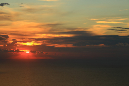 橙色的太阳躲在海面上的云层后面