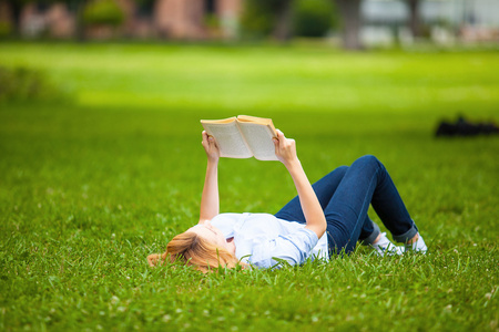 女人躺在草丛中，读一本书