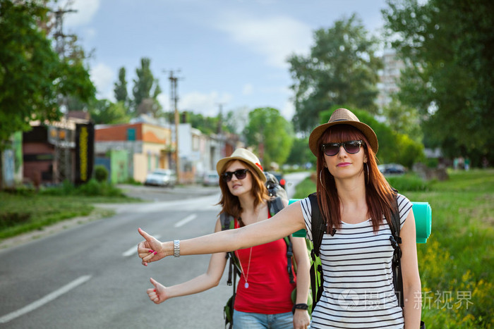 在公路上搭便车的旅游女孩