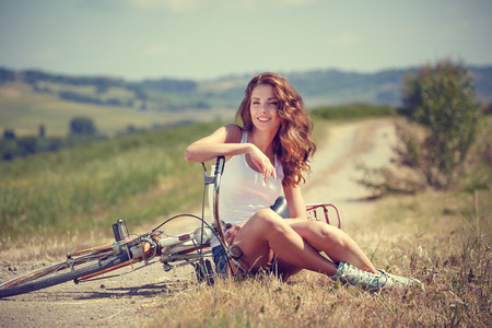 Vintage tjej sitter bredvid cykel老式的女孩坐在旁边的自行车
