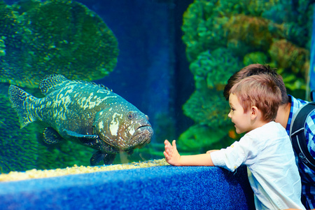 快乐的孩子沟通在水族馆的鱼