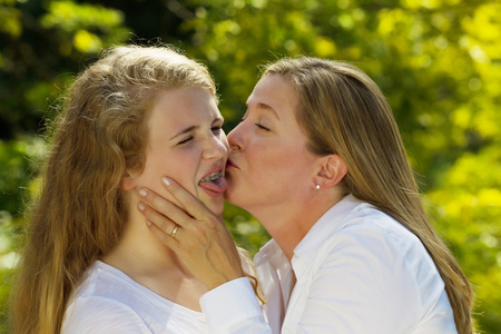 十几岁的女儿从她的母亲亲吻她不开心