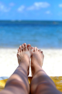 女孩的脚在沙滩上的背景下的海洋