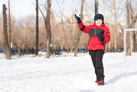 在冬季公园的男孩扔雪球