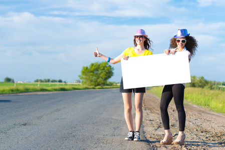 两个年轻女人站着一个空白的横幅