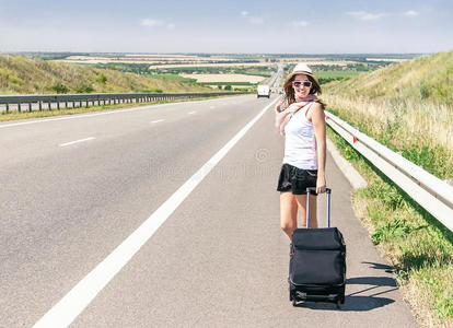 旅行者迷人的微笑女孩走在高速公路上。