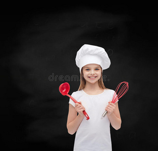 微笑的女孩戴着厨师帽，拿着勺子和搅拌器