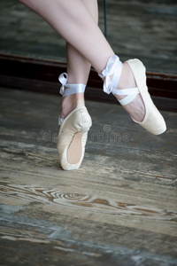 在木地板上穿着芭蕾舞鞋跳舞的脚
