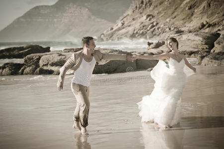 年轻迷人的情侣穿着白色衣服在海滩上调情