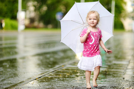 可爱的蹒跚学步的小女孩在雨中玩耍