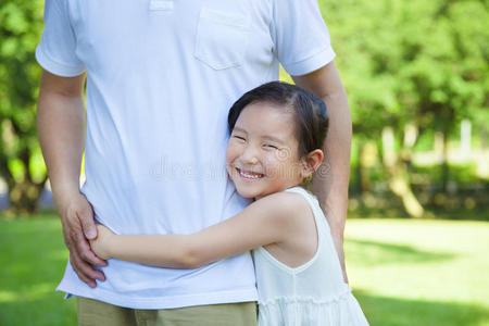 在公园里微笑的小女孩抱着爸爸的腰