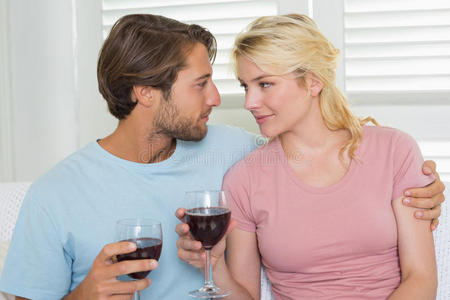 一对幸福的情侣在沙发上一起喝红酒