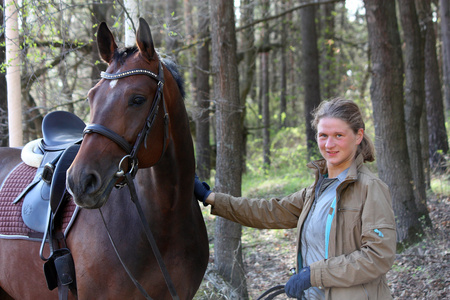 年轻女子和匹棕色的马一起在森林里