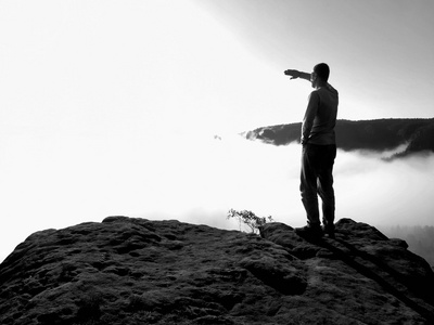 旅游穿着牛仔裤是站在国家公园萨克森瑞士砂岩的高峰期，到大太阳早晨迷雾笼罩的山谷注视