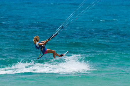 一个年轻女子的风筝冲浪运动员骑在蓝绿色的海洋