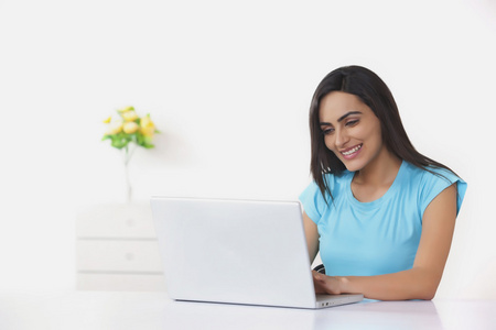 幸福的年轻女人在家里使用笔记本电脑