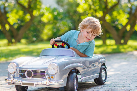 小男孩在户外驾驶大玩具辆旧车，
