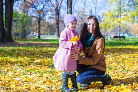 小女孩和年轻妈妈的秋色的公园，在阳光明媚的日子