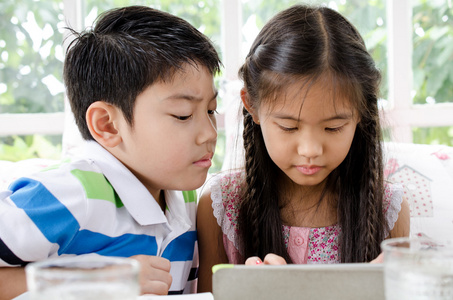 小小的亚洲女孩和男孩与平板电脑