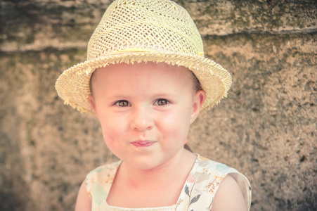 笑华丽和美丽的小女孩在一顶草帽