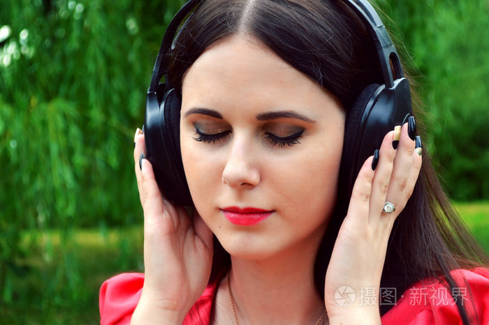 美丽的黑发女人在大耳机听音乐与她的眼睛闭上