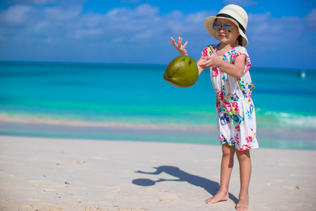 可爱的小女孩，用椰子在洁白的沙滩上玩得开心