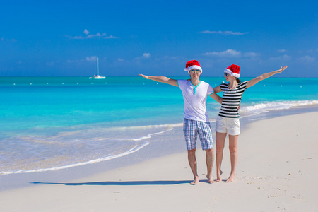年轻幸福的夫妇，在热带海滩上的红色圣诞帽。