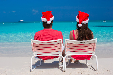 幸福浪漫的情侣在地处热带的海滩的红色圣诞帽。