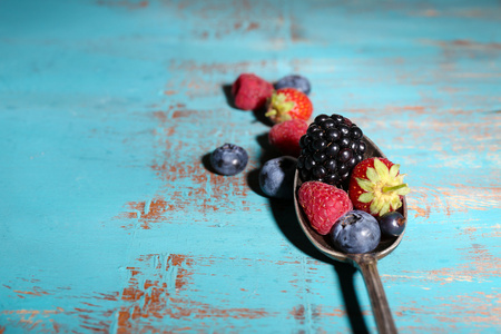 成熟甜的不同的莓果在老式的勺子，旧木制的桌子上