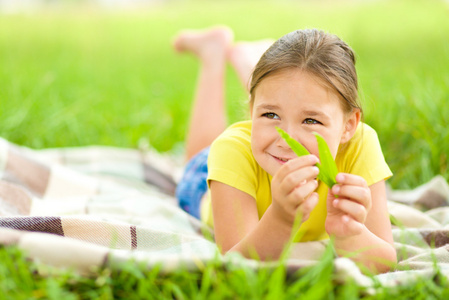 一个小女孩躺在绿色草地上的肖像