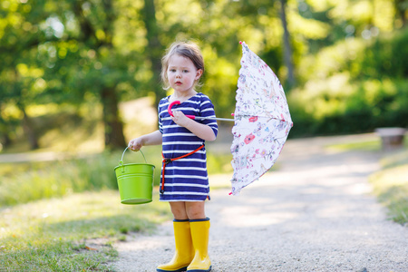 可爱的小孩子的黄雨靴和雨伞在夏天干了什么