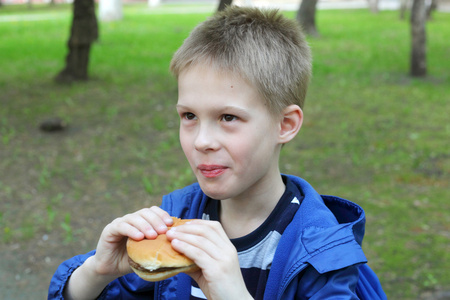 男孩在公园里吃汉堡包